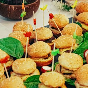 Retail A vibrant display of mini burgers with skewers at a catering event, highlighting festive food presentation.